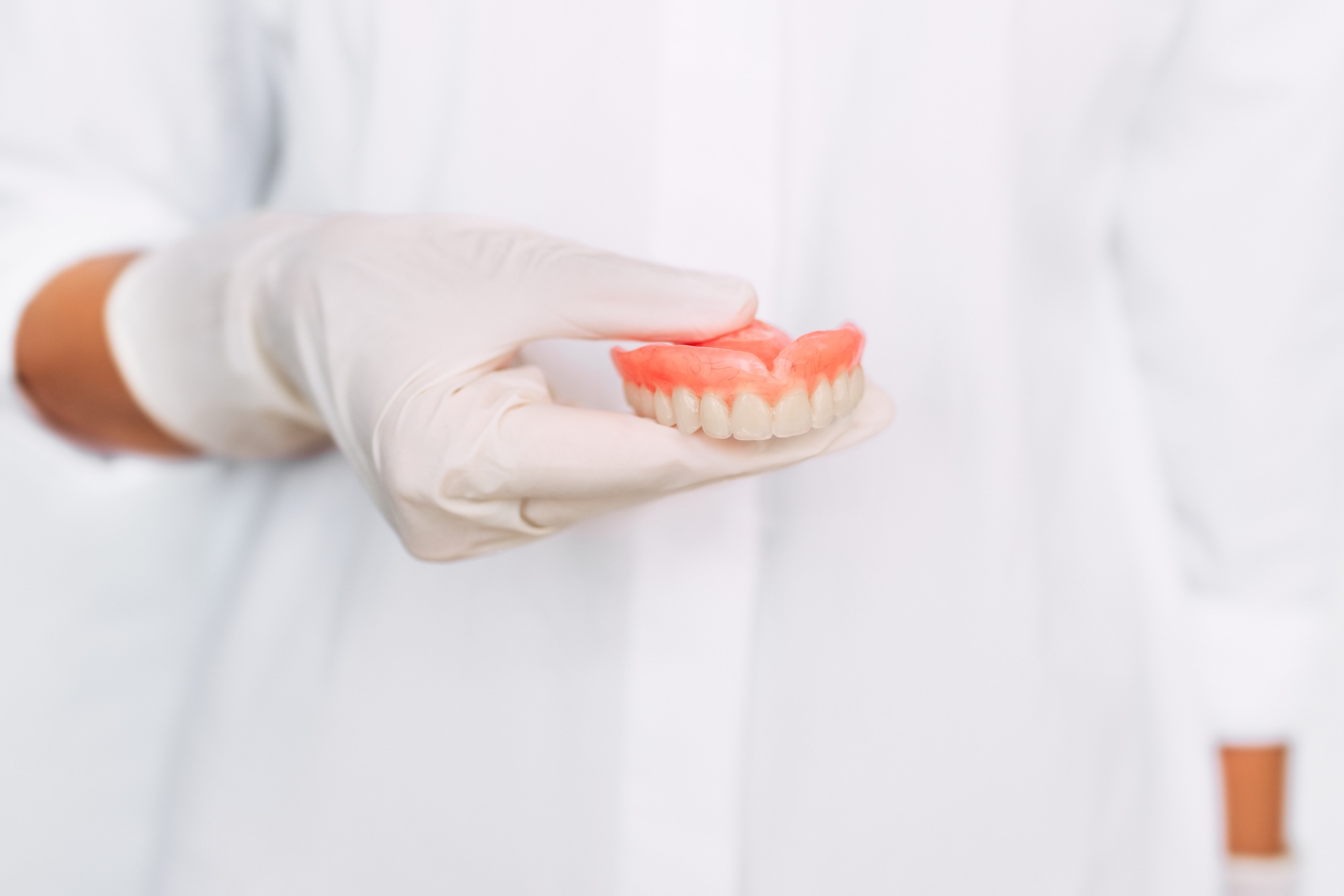 The dentist is holding dentures in his hands. Dental prosthesis in the hands of the doctor close-up